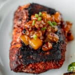 Blackened cod topped with peach chutney with text overlay.
