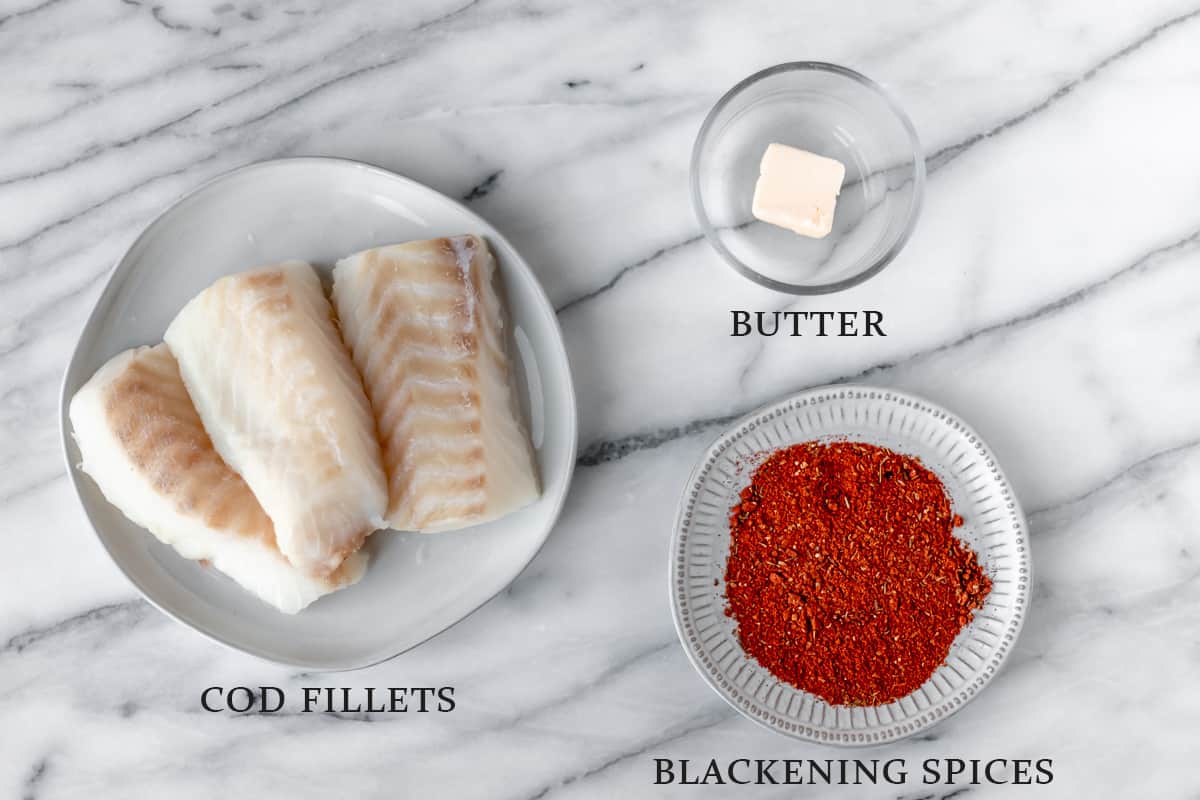 Ingredients needed to make blackened cod on a marble background with text overlay.