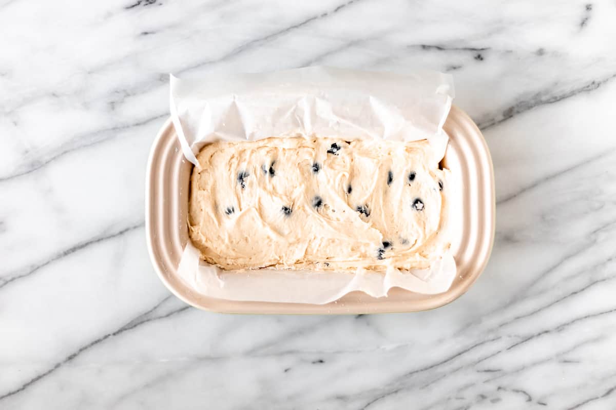 Blueberry lemon pound cake batter in a loaf pan on a marble background.