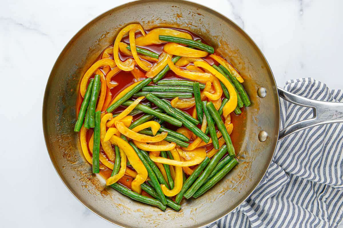 Green beans, yellow bell pepper and sauce in a skillet.
