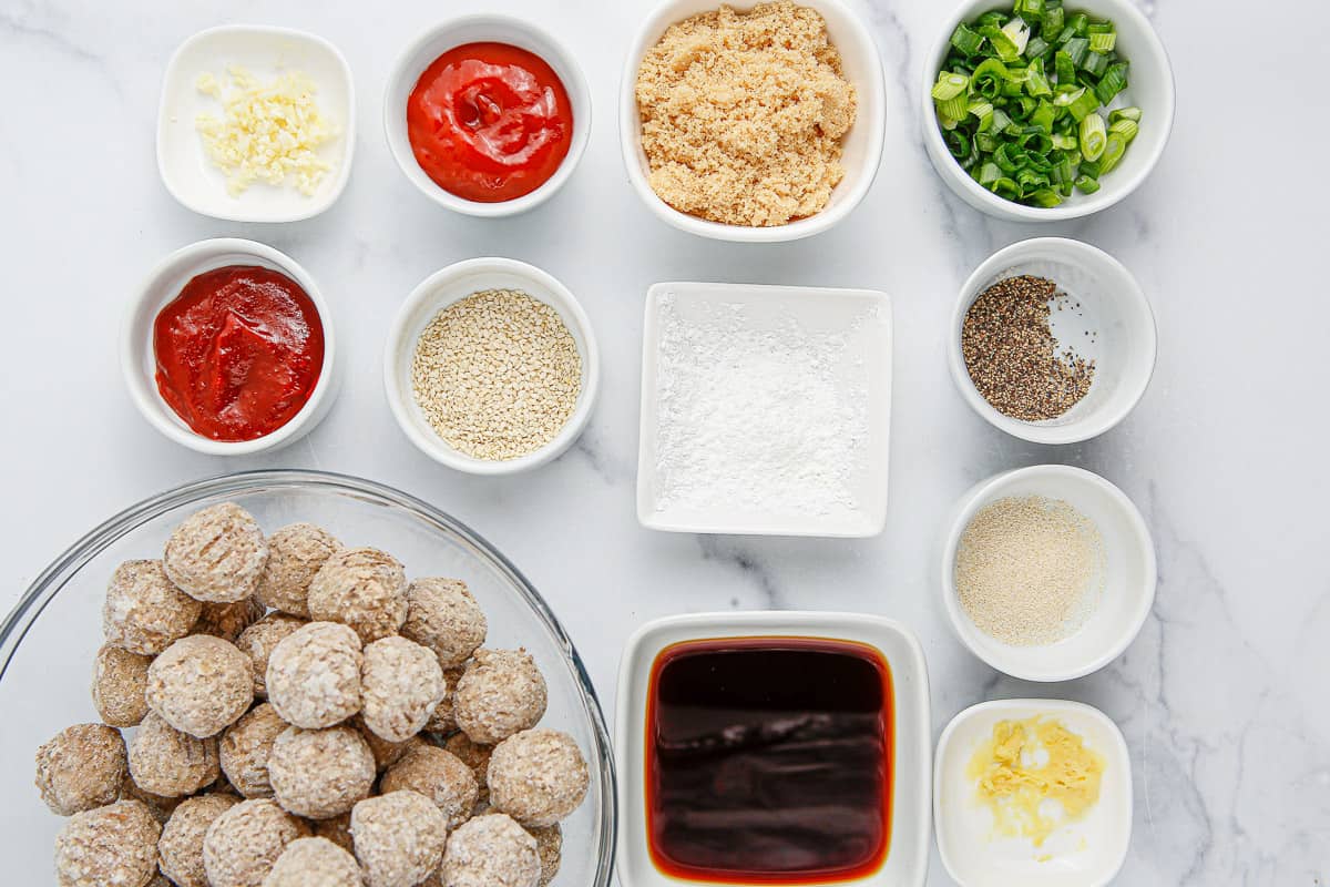 Ingredients for making Korean BBQ meatballs in dishes and bowls on a marble background.