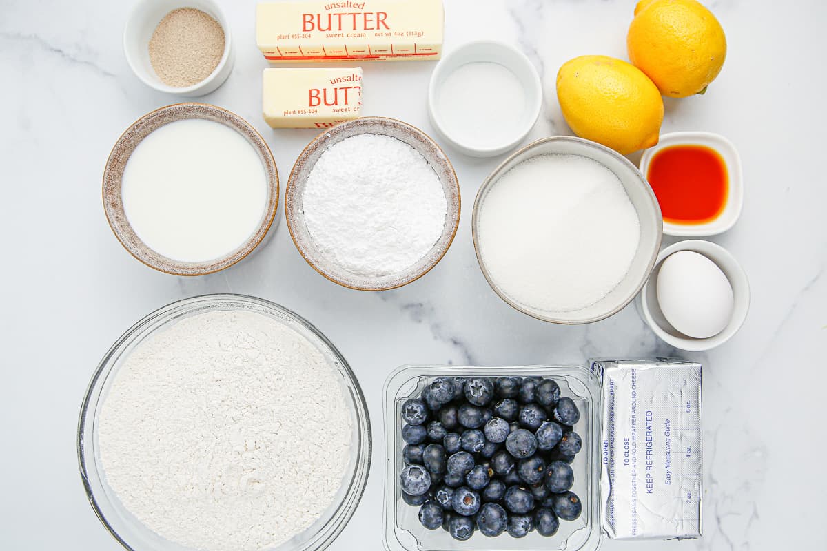 Ingredients needed to make lemon blueberry sweet rolls on a white background.