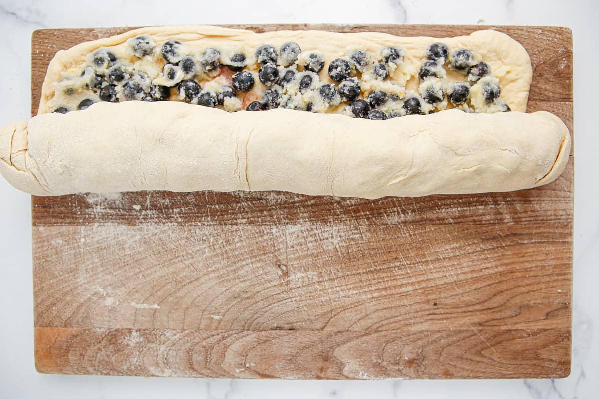 Lemon blueberry mixture being rolled up into dough.