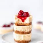 Mini cheesecakes stacked and topped with cherries with text overlay.