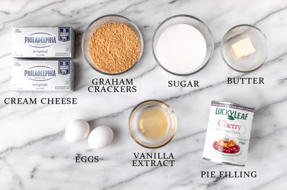 Ingredients needed to make mini cheesecakes on a marble background with text overlay.