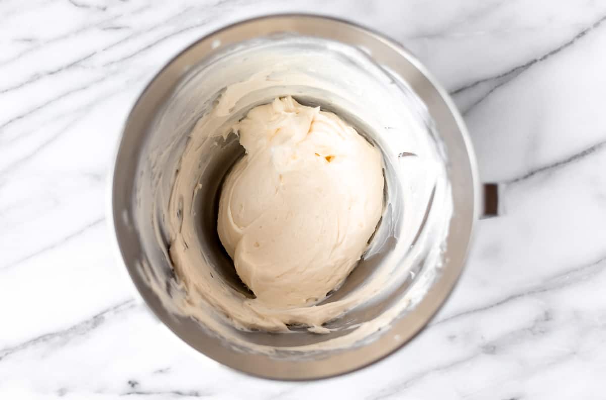 Whipped cream cheese, sugar and vanilla in a silver mixing bowl.