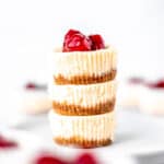Mini cheesecakes stacked and topped with cherries with text overlay.