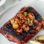 Blackened fish topped with peach chutney with text overlay.