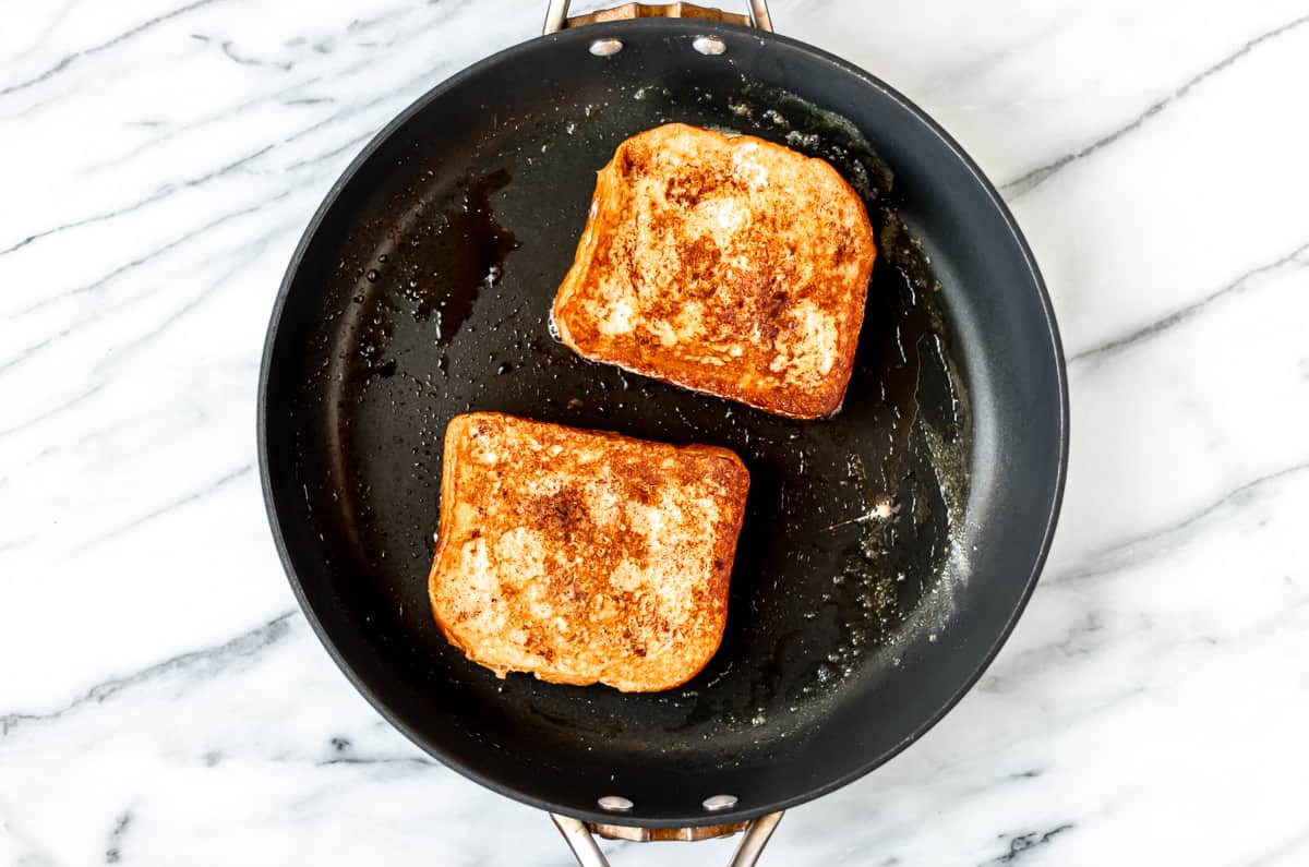 Cooked stuffed french toast in a black skillet.