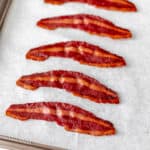 Baked turkey bacon on a parchment paper lined baking sheet.