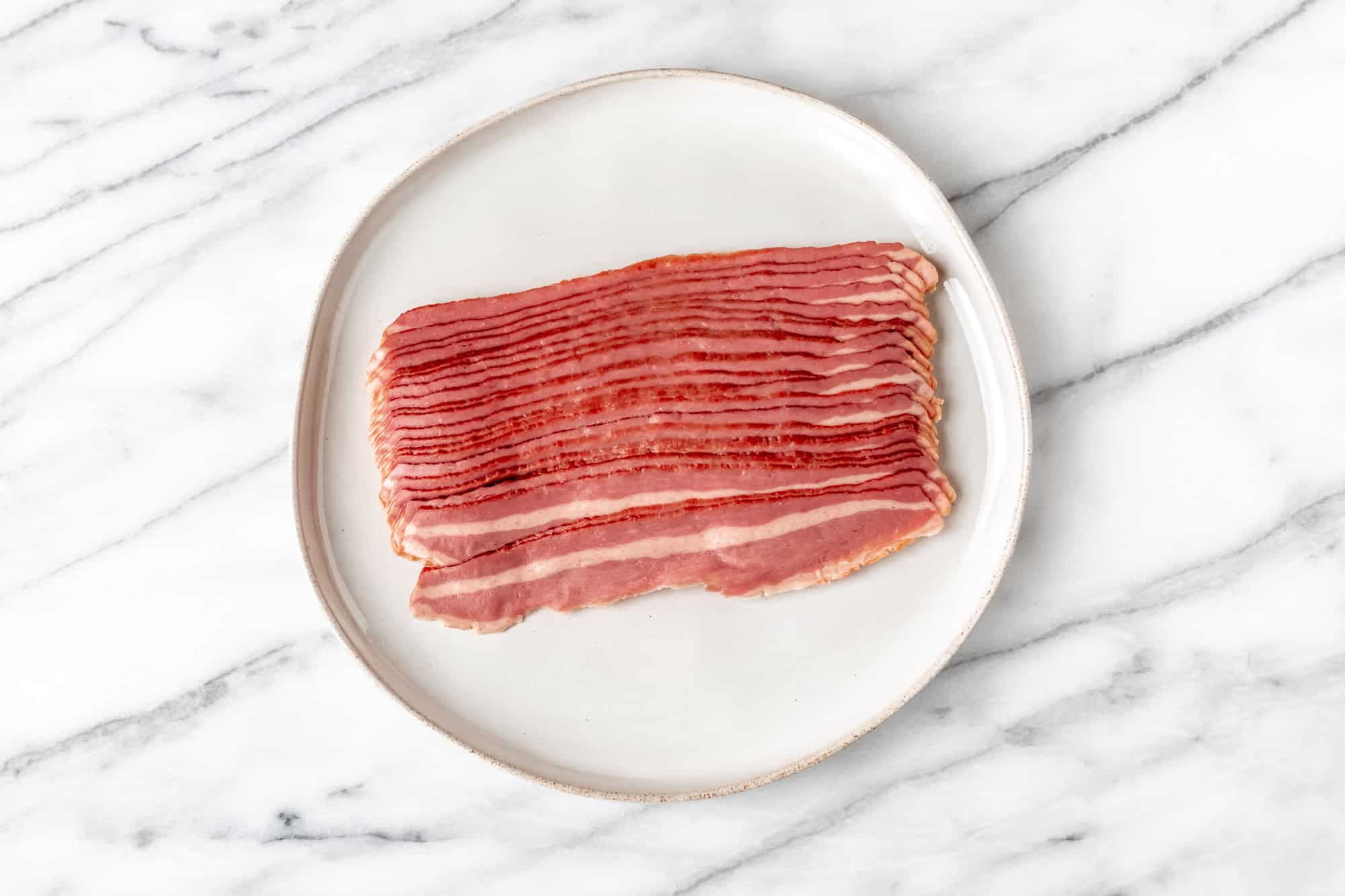 Turkey bacon on a white plate on a marble background.