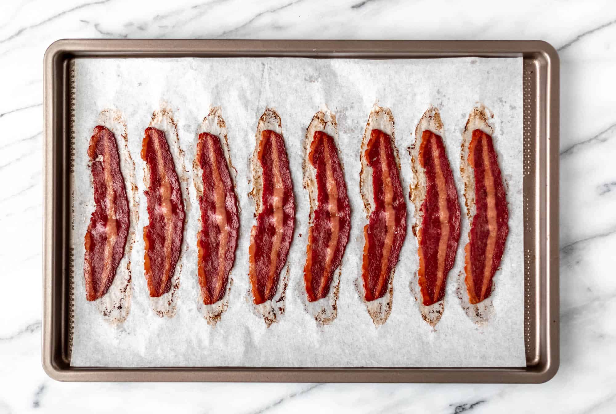 Cooked turkey bacon on a parchment paper lined baking sheet.
