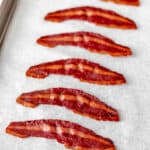 Turkey bacon on a parchment paper lined baking sheet with text overlay.