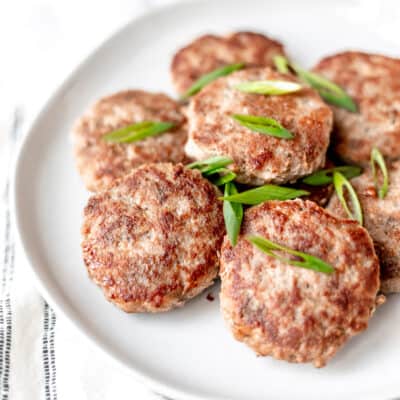 Turkey sausage patties on a white plate with sliced scallions.
