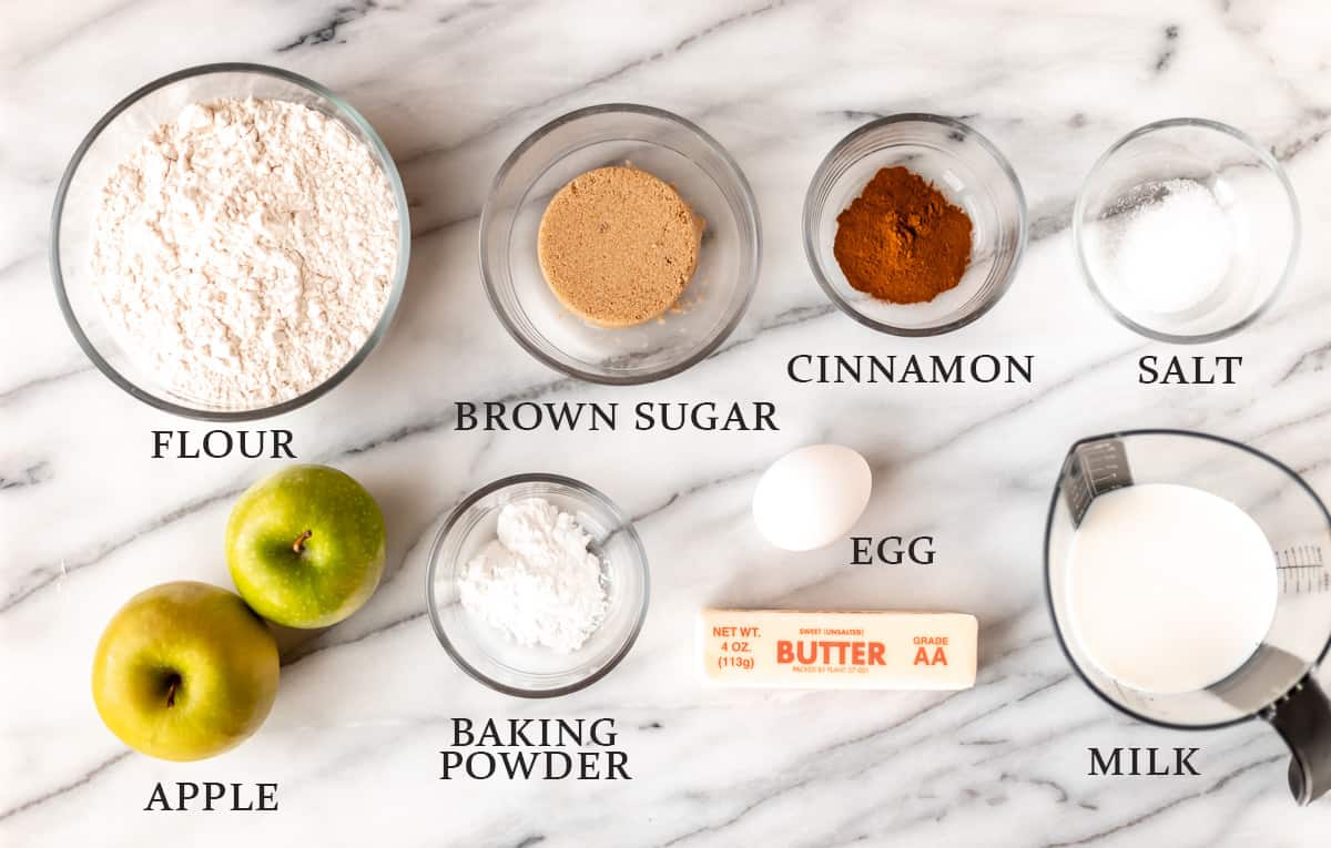 Ingredients to make apple cinnamon scones on a marble background with text overlay.
