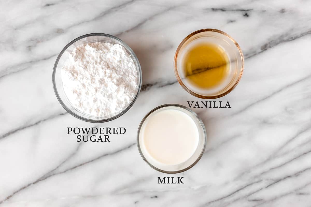 Ingredients to make vanilla glaze on a marble background with text overlay.