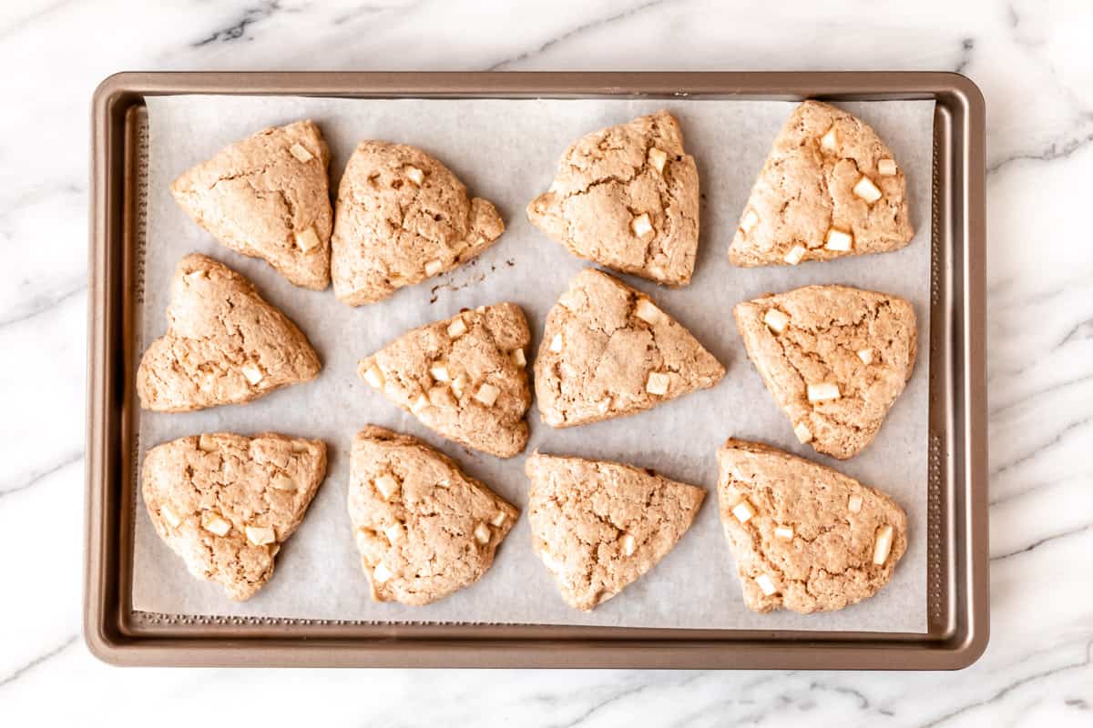 12 baked apple cinnamon scones on a parchment paper lined baking sheet.