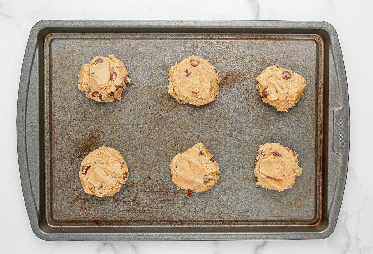 Chocolate chip cookie dough balls on a baking sheet.