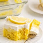 Lemon poke cake on a plate with a piece on a fork and text overlay.