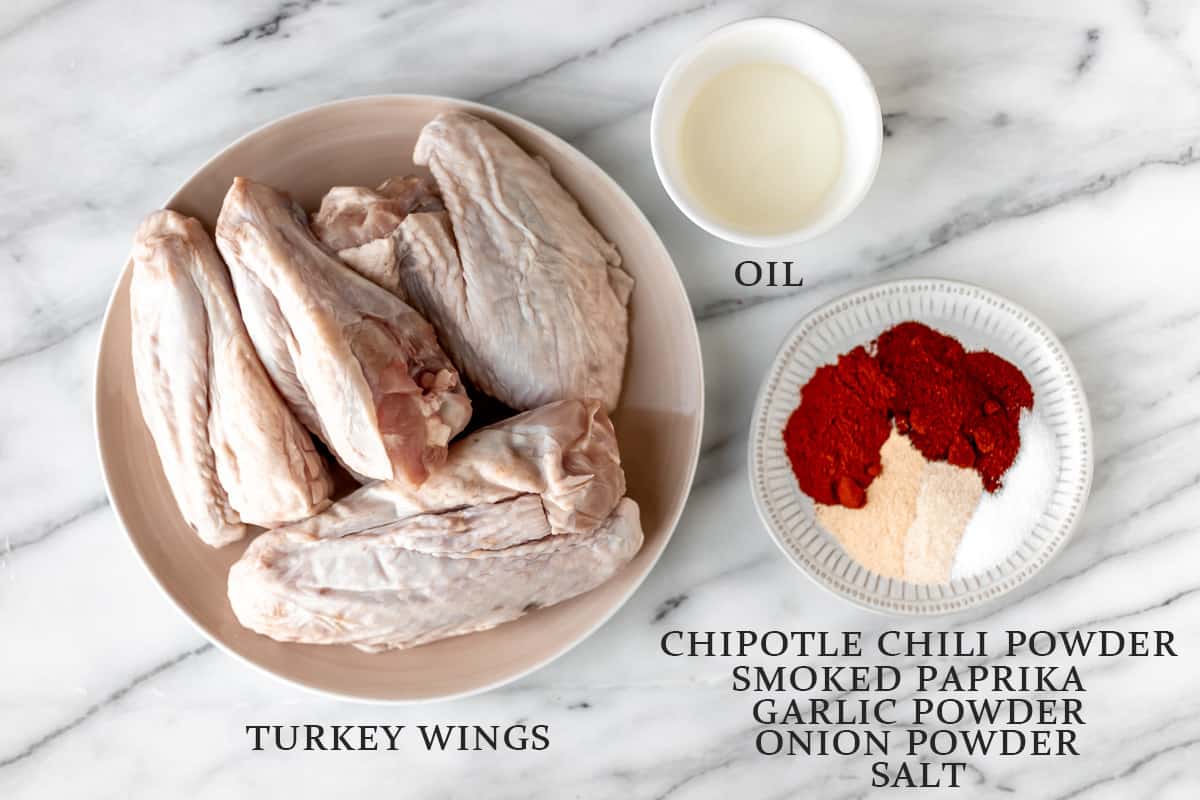 Ingredients needed to make smoked turkey wings on a marble background with text overlay.
