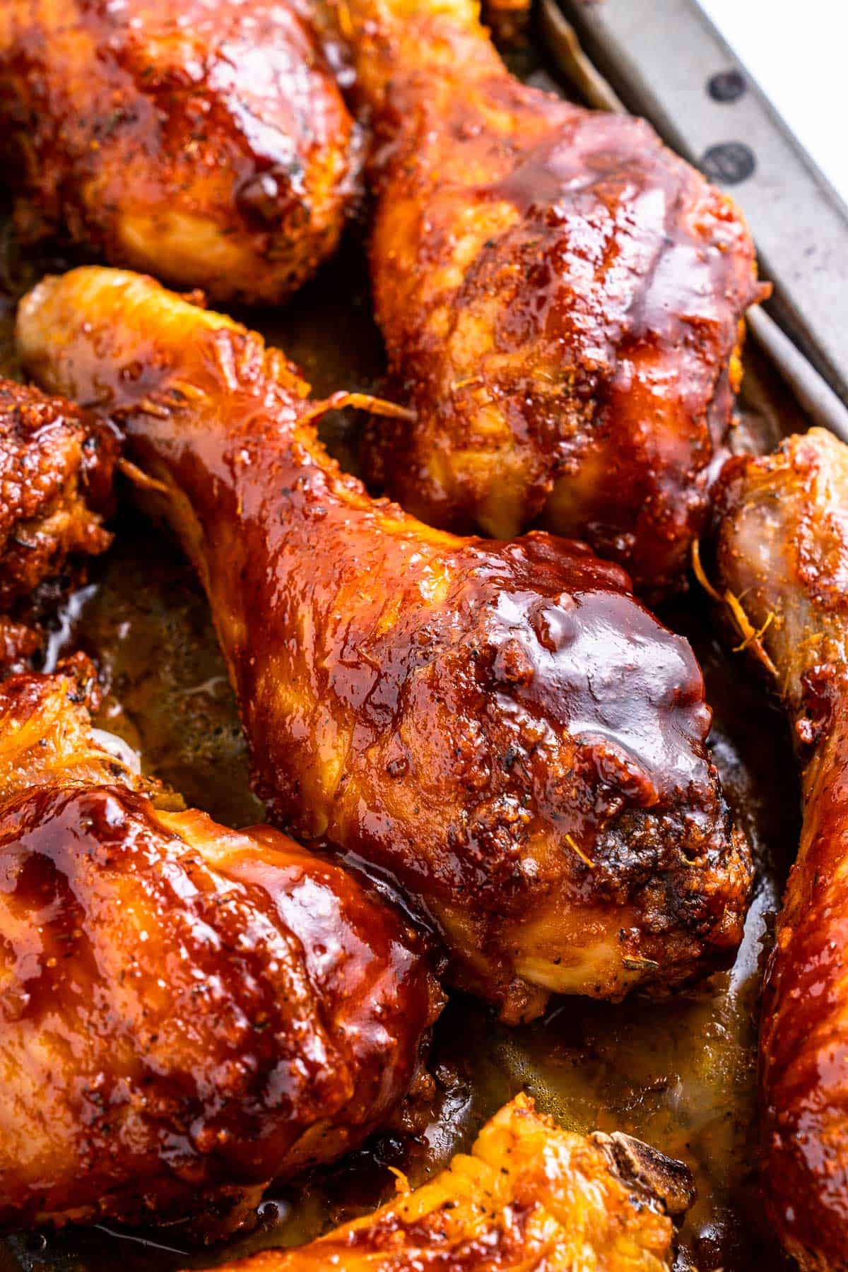 Close up of baked bbq chicken drumsticks on a sheet pan.
