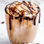 Close up of an ice mocha latte with chocolate drizzle over a white background.
