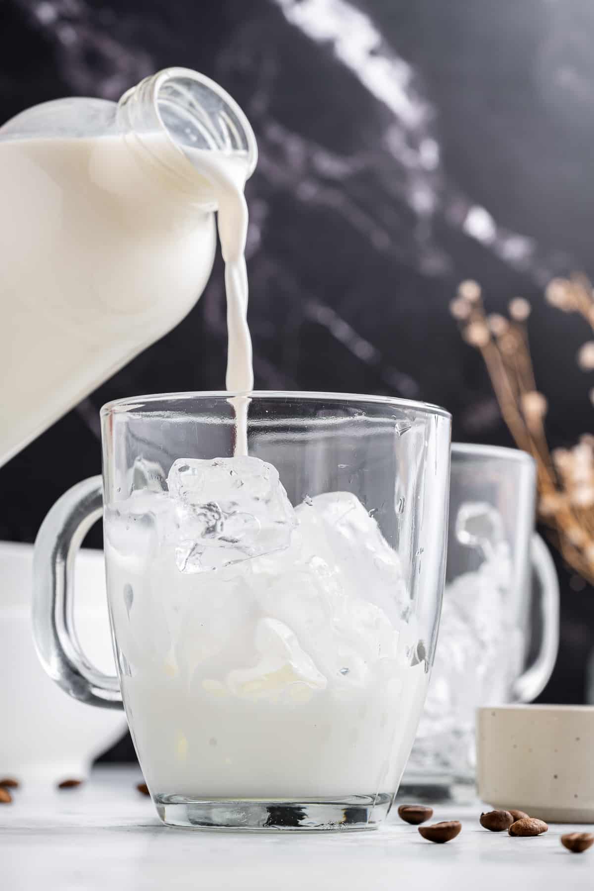 Milk being poured into a glass of ice.