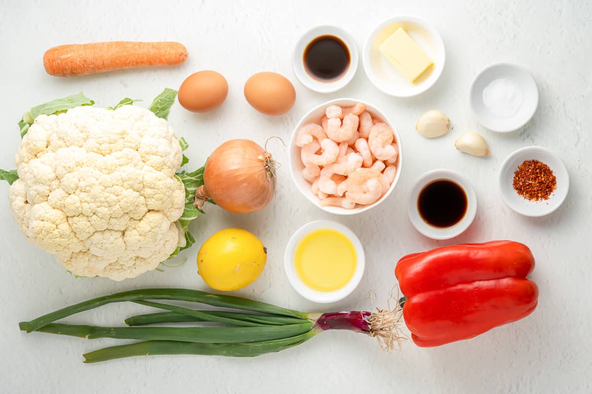 Ingredients needed to make shrimp cauliflower fried rice on a white background.