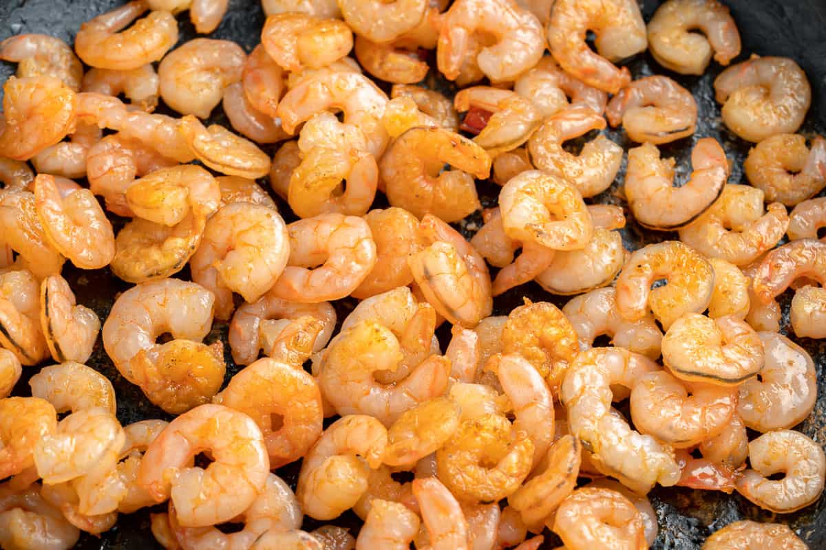 Close up of cooked shrimp in a skillet.