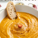 Spicy pumpkin soup in a white bowl with bread and text overlay.