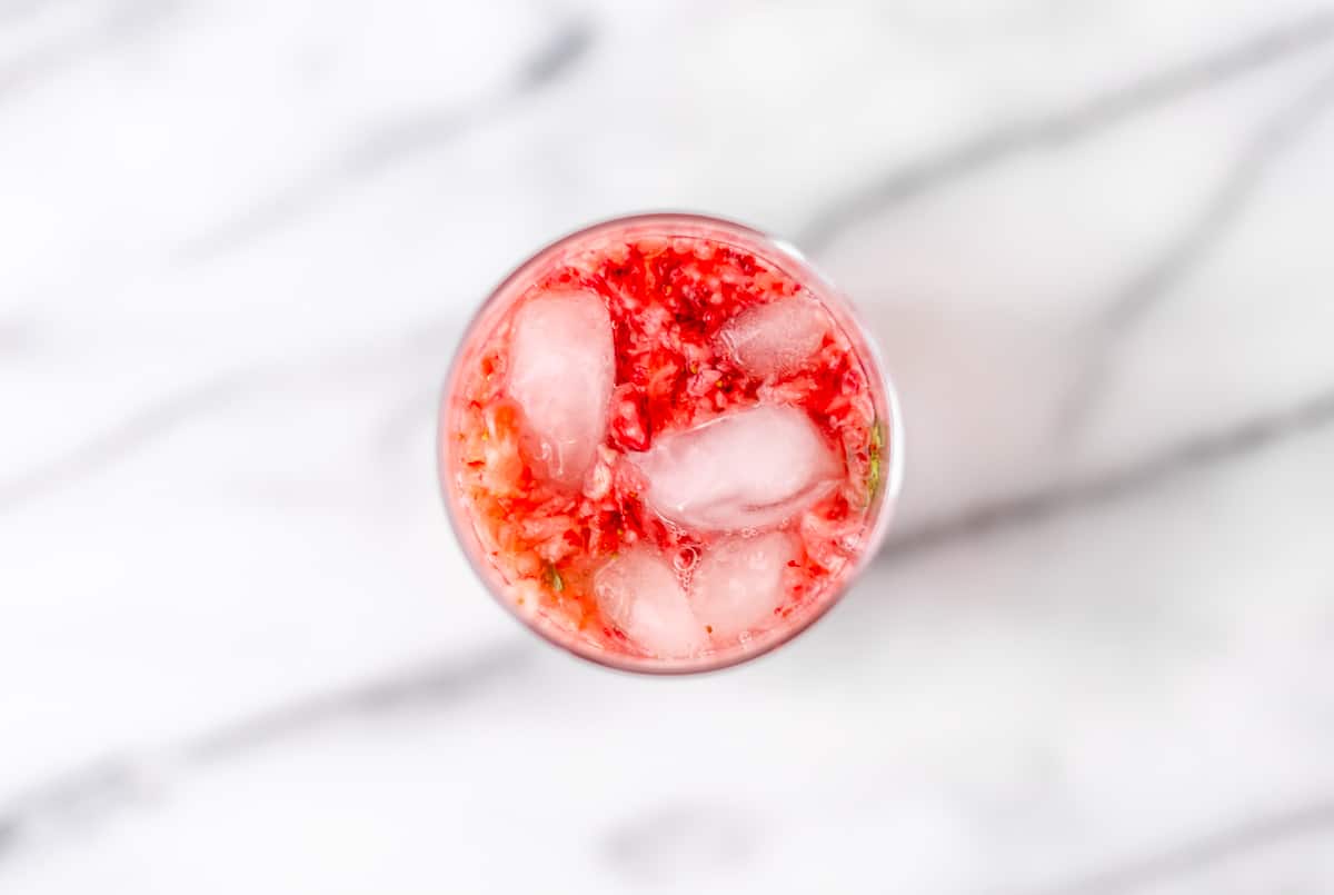 Overhead of strawberry mojito with ice over a marble background.