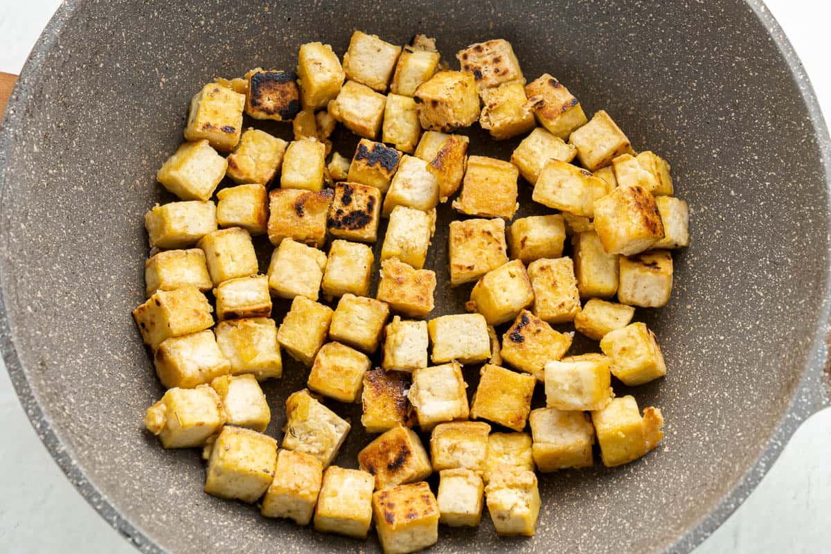 Fried tofu cubes in a skillet.