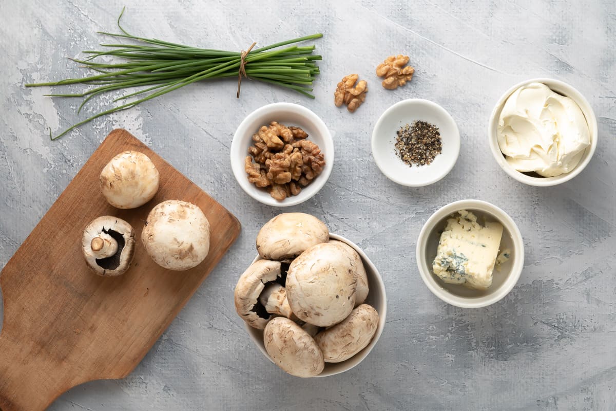 Ingredients needed to make vegetarian stuffed mushrooms on a gray background.