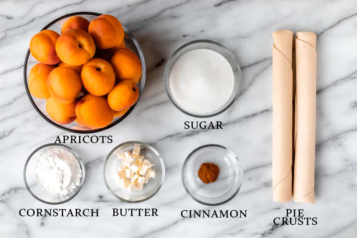 Ingredients needed to make an apricot pie on a marble background with text overlay.