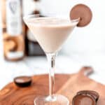 A chocolate peanut butter martini on a wood server with Reese's cups around it and text overlay.