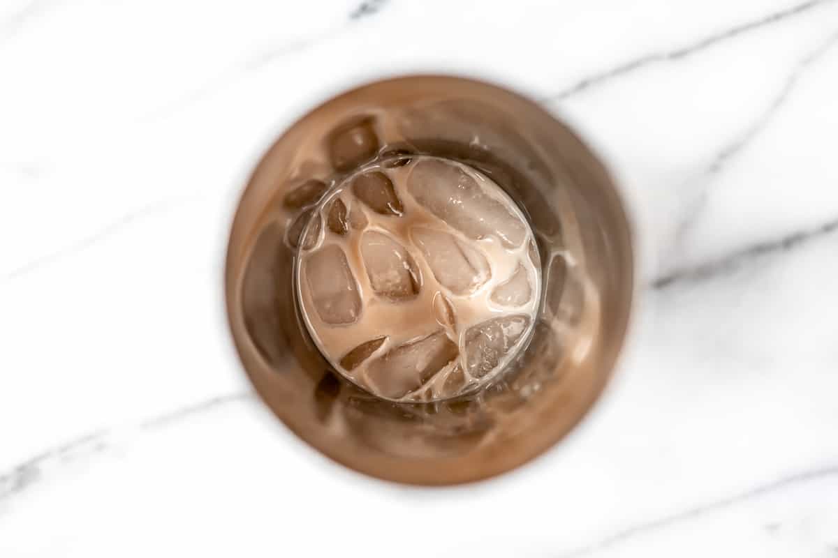 Overhead of a cocktail shaker with ice and liqueur in it.
