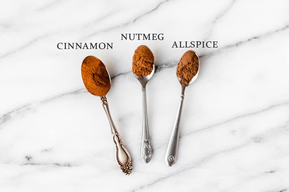 Ingredients needed to make apple pie spice on spoons with text overlay.