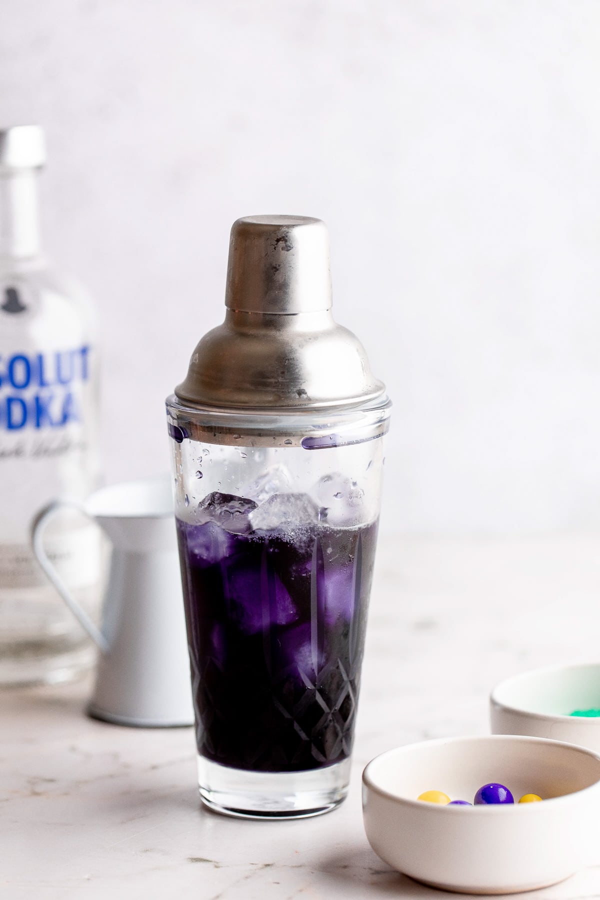 A cocktail shaker with purple liquid inside.