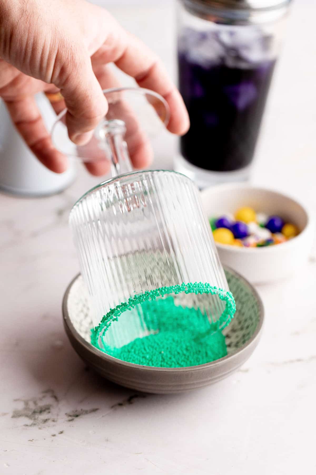A glass being dipped into green sprinkles.