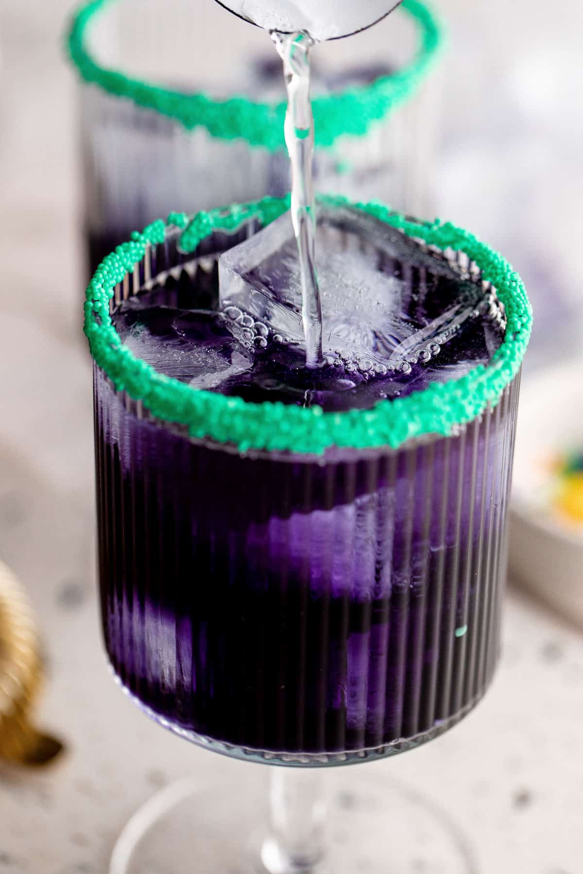 Sprite being poured into a purple cocktail.