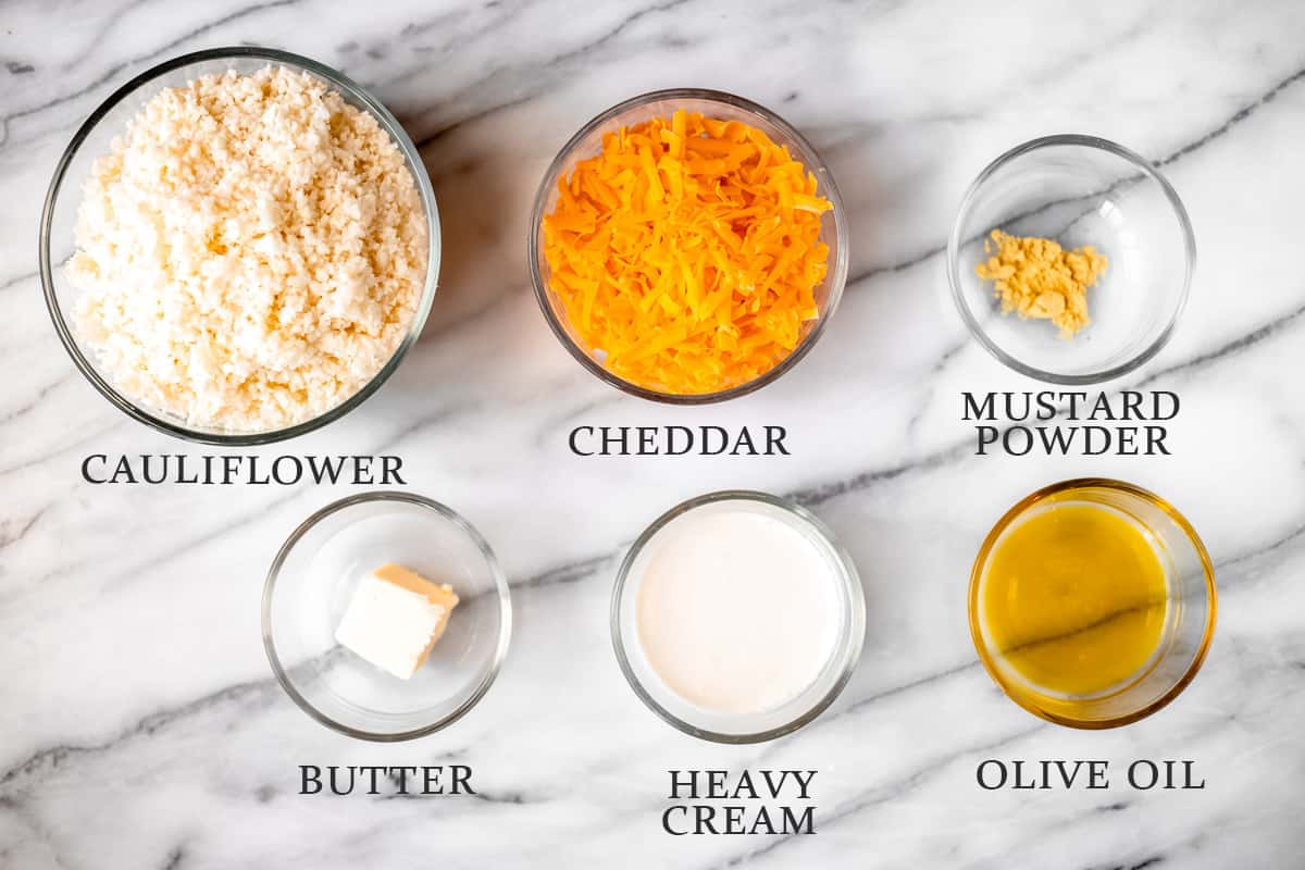 Ingredients needed to make cheesy cauliflower rice on a marble background with text overlay.