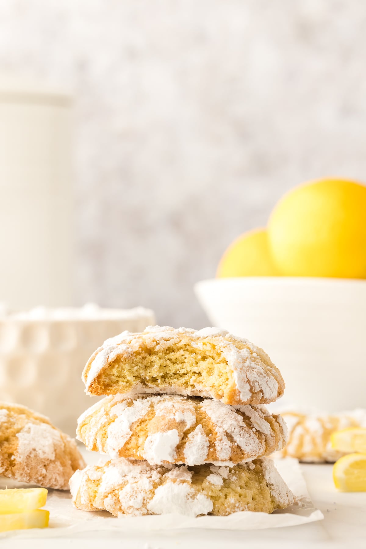 Lemon crinkle cookies with lemons in the background.
