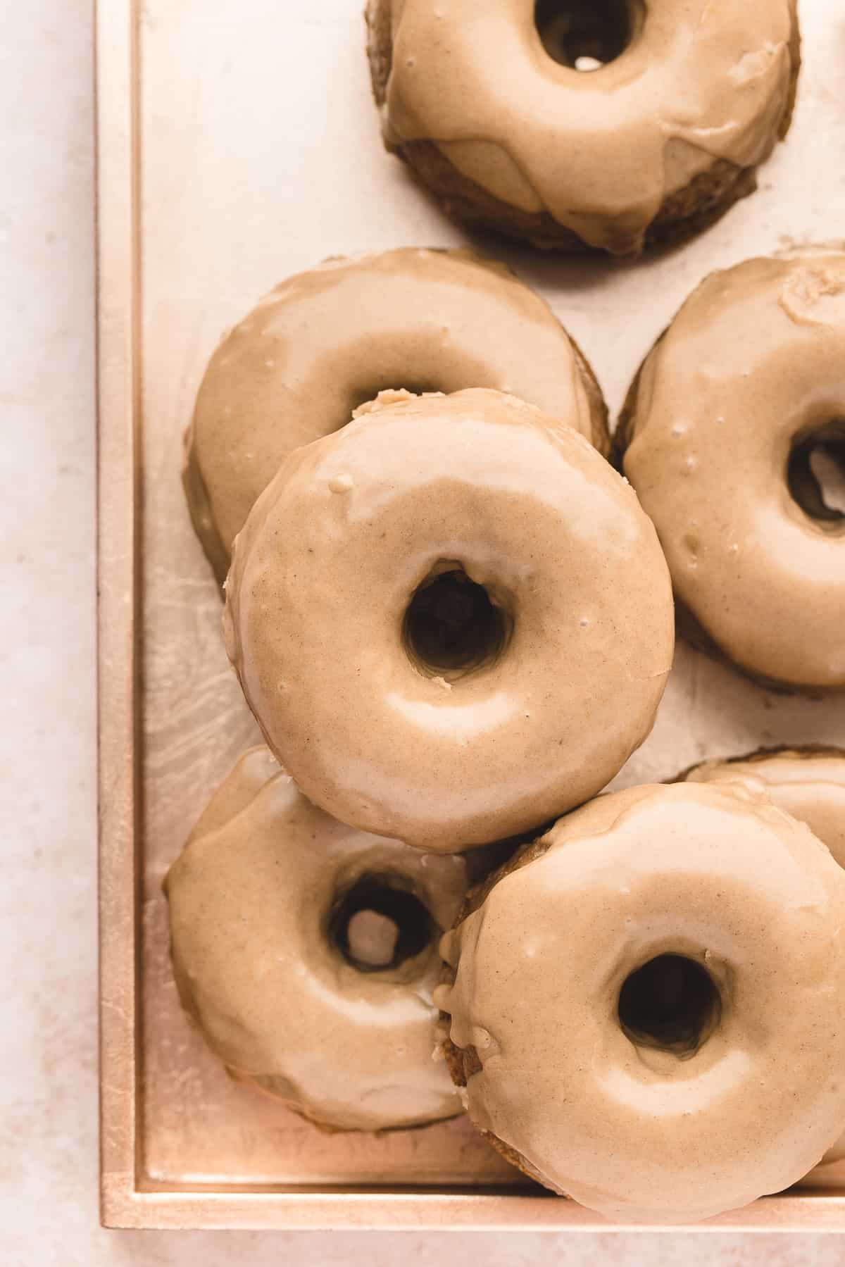 Overhead of a tray of maple glazed pumpkin donuts.