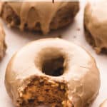 Pumpkin donuts with maple glaze and a bite taken out with text overlay.
