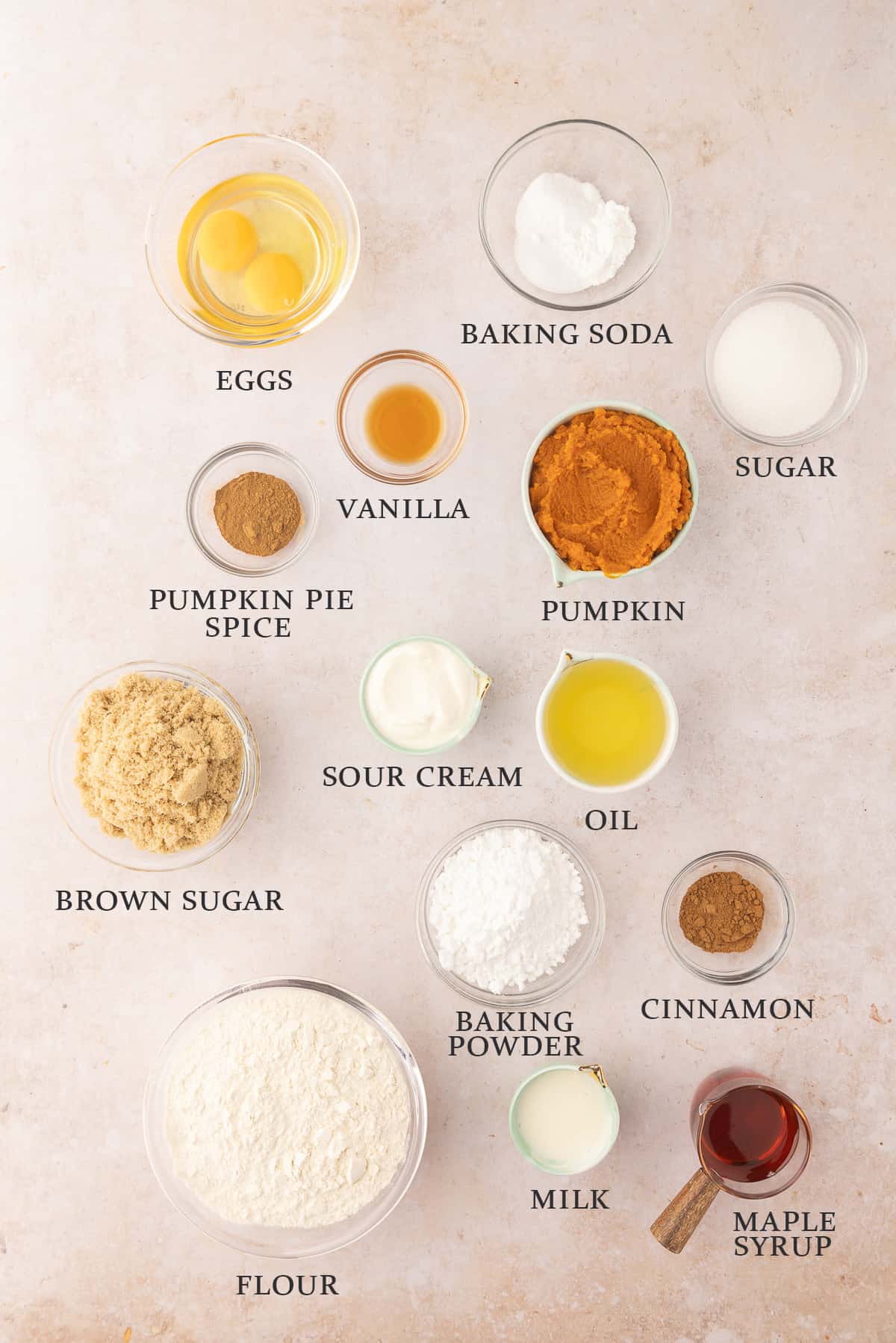 Ingredients needed to make pumpkin donuts and maple glaze on a light pink background with text overlay.