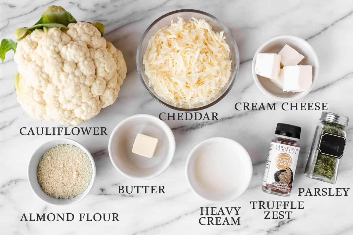 Ingredients needed to. make truffle cauliflower mac and cheese on a marble background with text overlay.