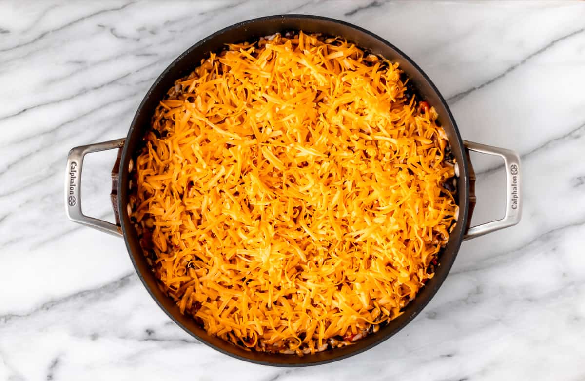 Shredded cheese on top of a taco skillet before melting.