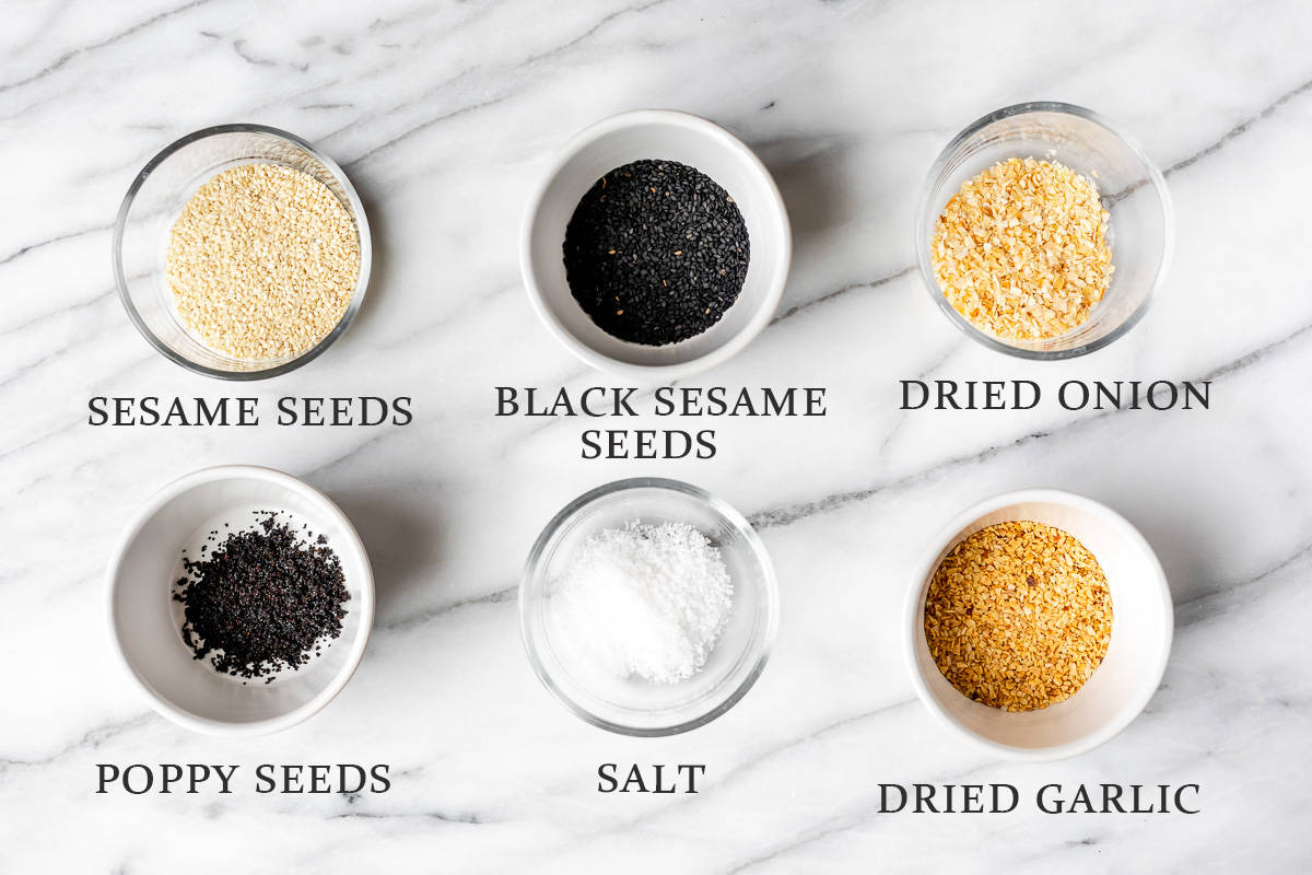 Ingredients needed to make everything bagel seasoning in small white and clear bowls with text overlay.