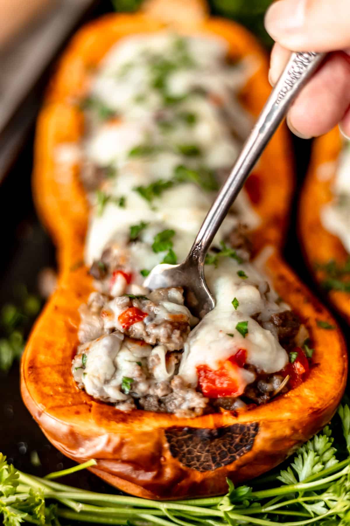 Close up of a stuffed butternut squash with a fork in it lifting some of the filling up.