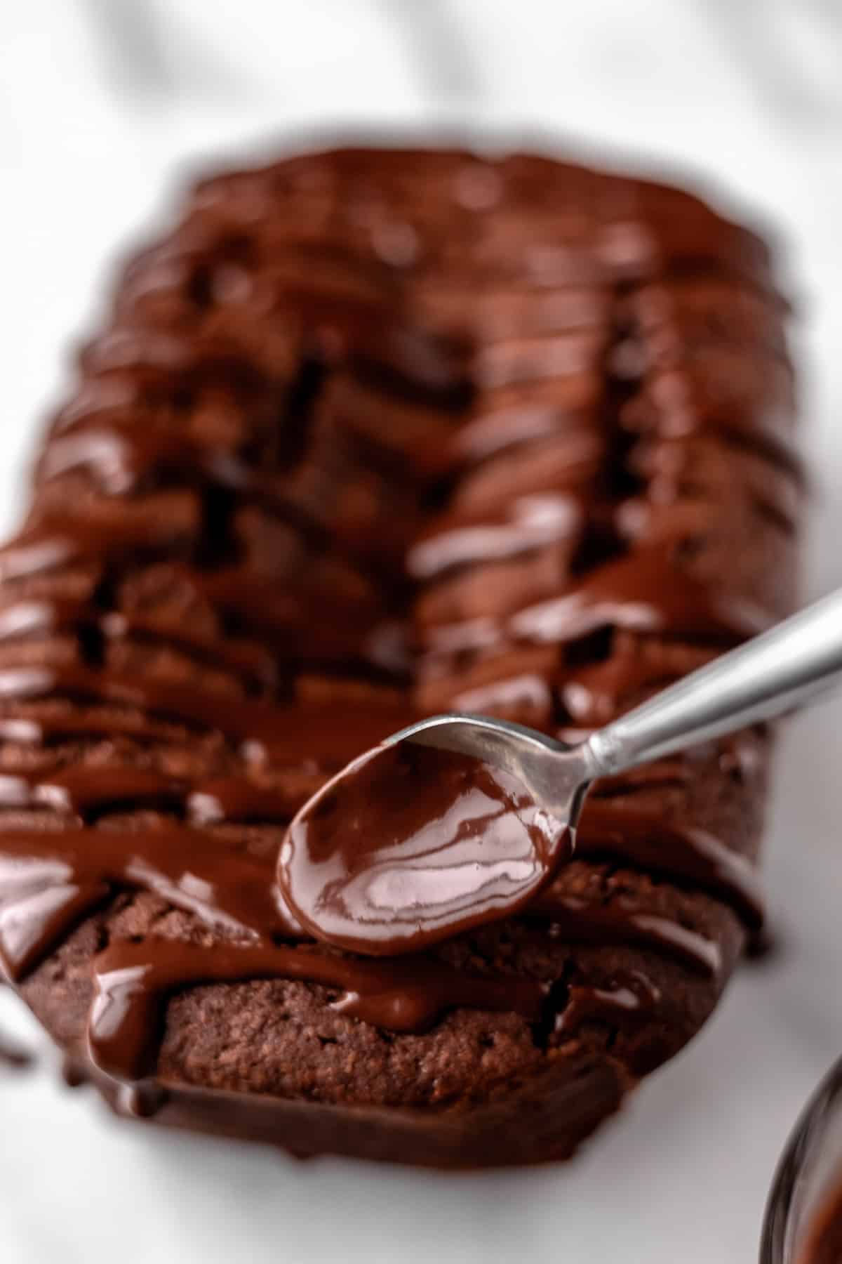 Close up of chocolate glaze being drizzled on top of a chocolate pound cake.